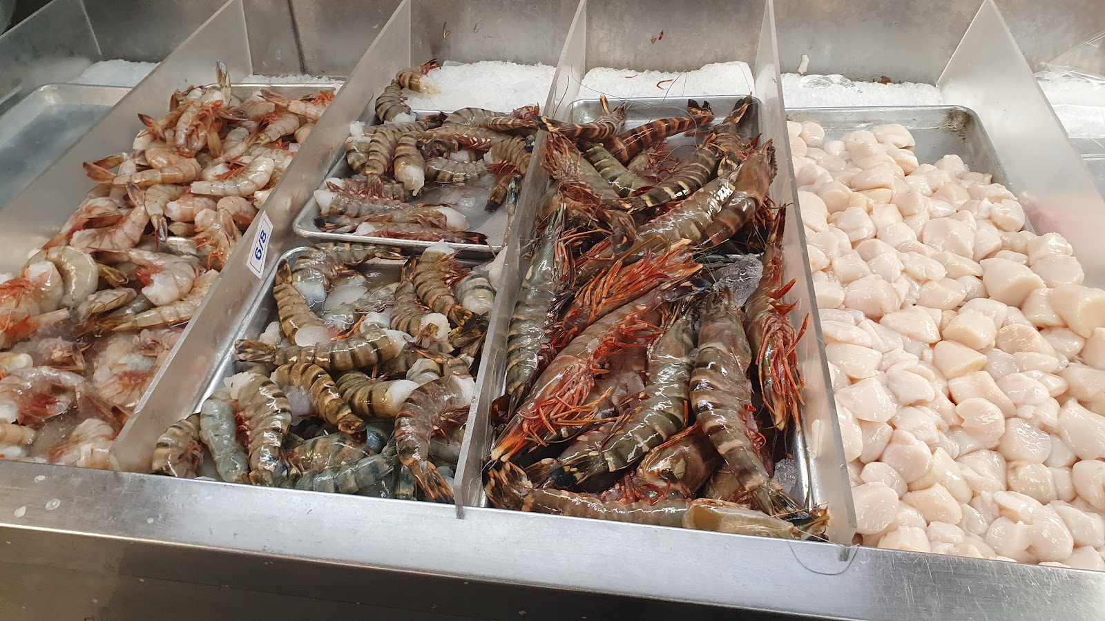 Fresh shrimp and scallops on ice at the market counter